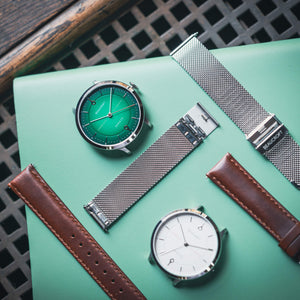 A green and white face mechanical watch with leather and metal strap options