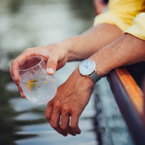 The wrist of a man wearing the stone Grey Beaucroft Senate watch on a punt in Cambridge
